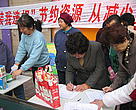 Beijing residents pledge to reduce their plastic bag usage at the WWF initiated "20 ways to 20%" energy saving campaign event. On display are bags made from recycled dairy cartons to demonstrate creative ways to reuse and recycle. Behind them is a banner saying: "Reduce plastic bag use to save energy."
